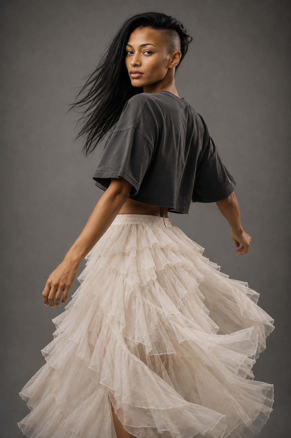 Dshana, female AI fashion model in a charcoal cropped T-shirt and flowing ivory tulle skirt, dynamic studio fashion editorial by VIDA AI