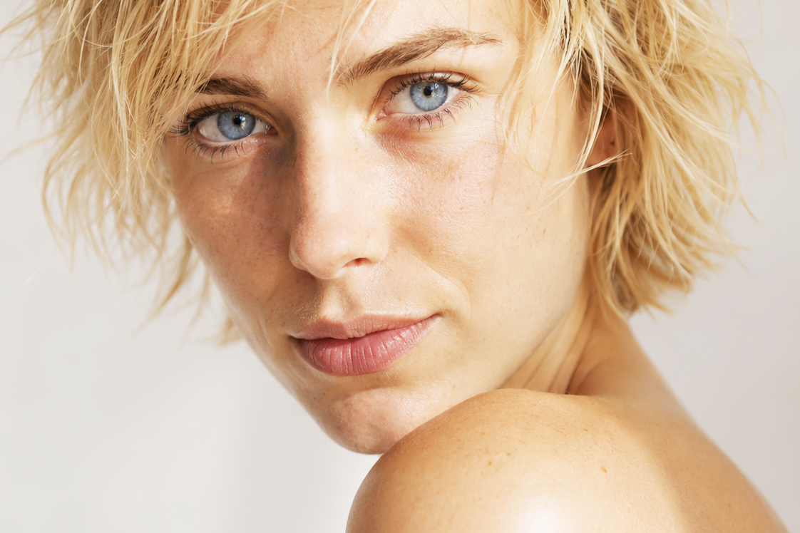 Juli, female AI fashion model with short blonde hair, blue eyes and natural freckles, close-up beauty portrait by VIDA AI
